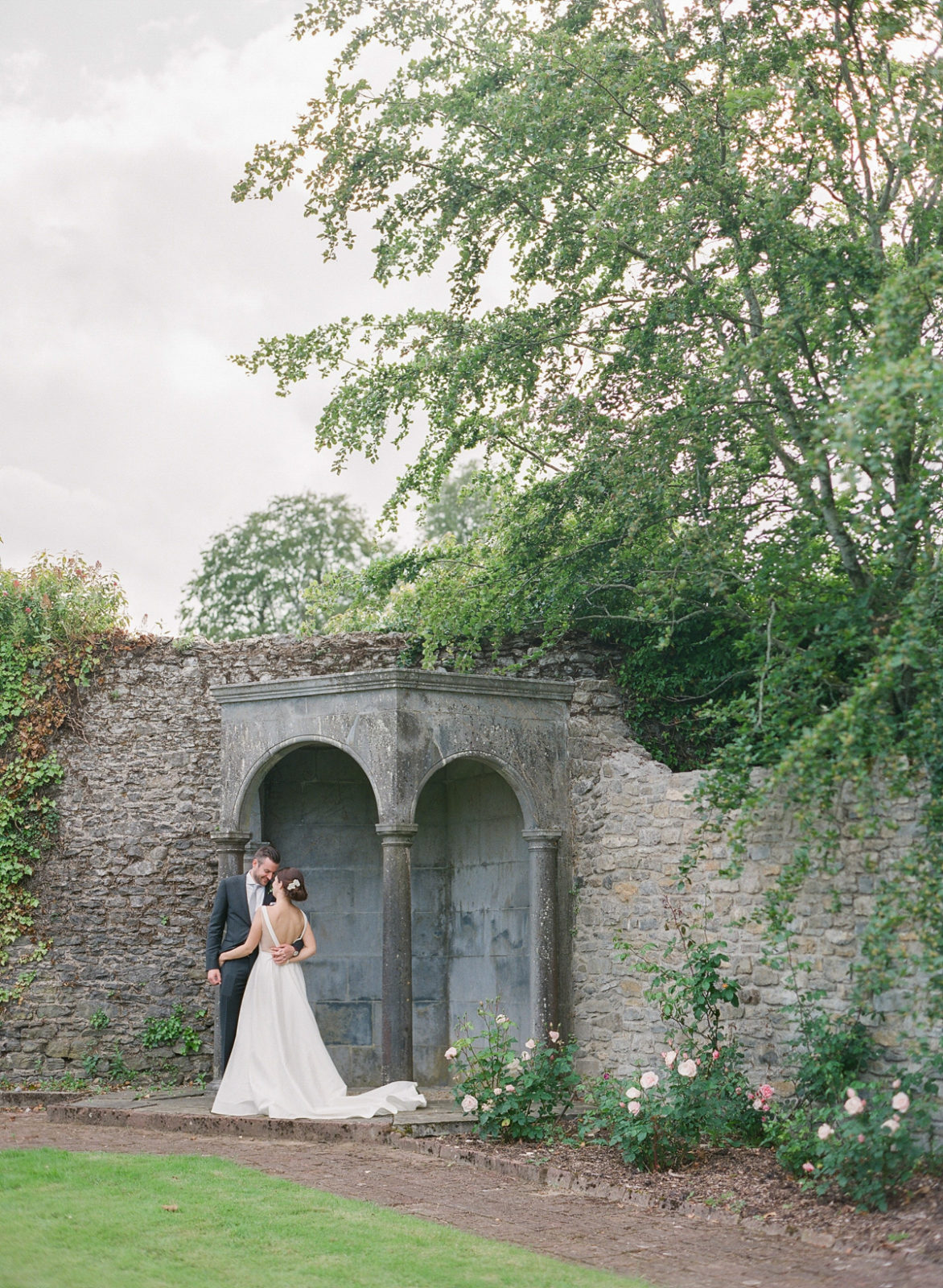 Ireland Film Photographer | Molly Carr Photography | Bride in White Jenny Yoo Wedding Dress and Groom in Grey Suit Kissing in Mount Juliet Estate Walled Irish Garden
